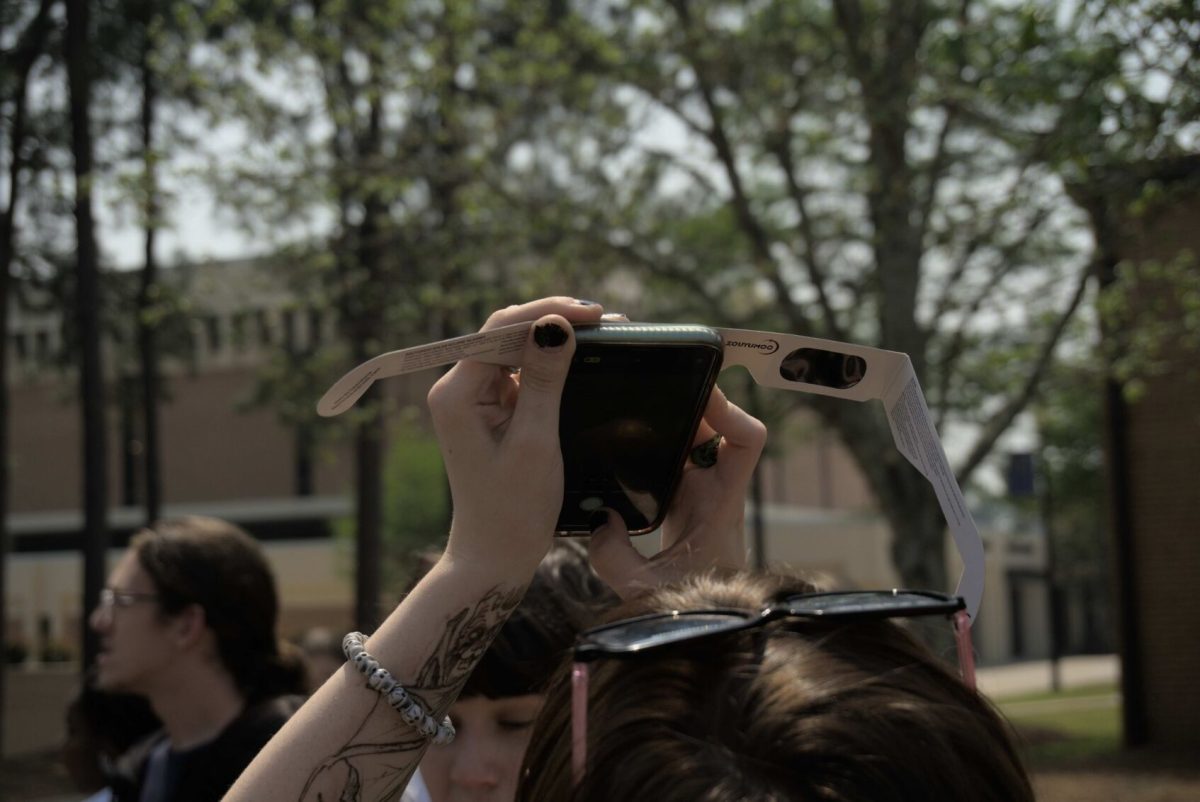 A student takes a photo of the phenomenon through a pair of solar eclipse glasses.